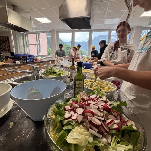 Schüler richten in der Küche grünen Salat und Kartoffelsalat her