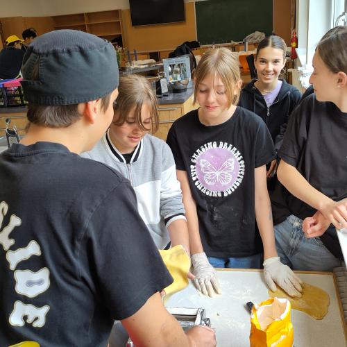 Ein PTS Schüler macht mit Hilfe der Nudelmaschine mit ein paat Mittelschüler Nudeln