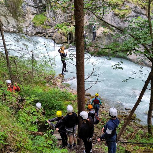 Schüler warten vor der Hängebrücke, einzelne Schüler klettern über den Inn
