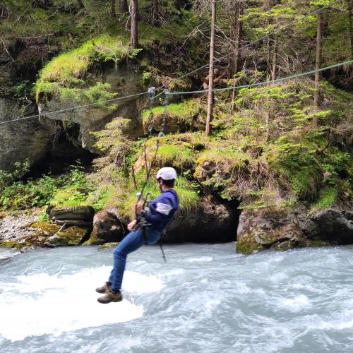 Ein Schüler rutscht über eine Seil über den Inn