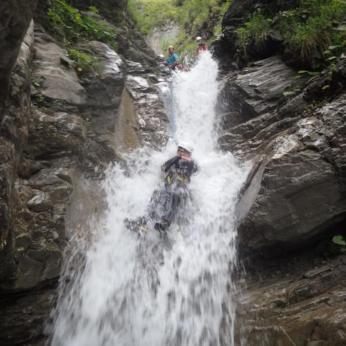 Ein Schüler, der im Wasserfall an einem Seil hängt