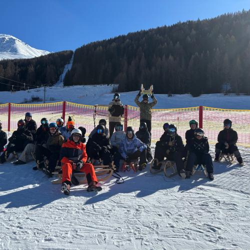 Gruppenfoto der Schüler:innen, die auf ihre Rodeln sitzen.