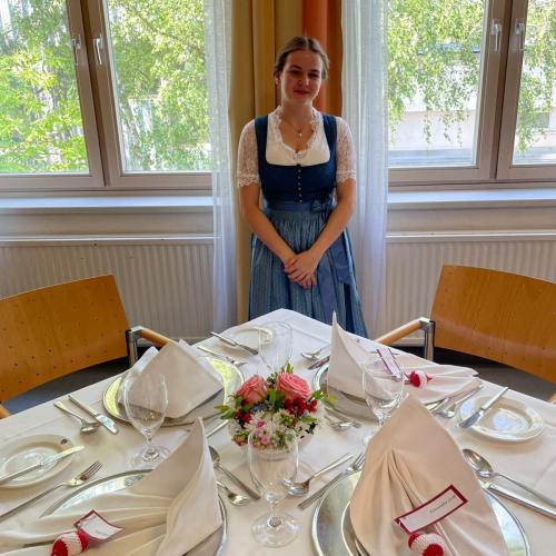 Schülerin im Dirndl steht bei ihrem gedeckten Tisch beim Bundeswettbewerb