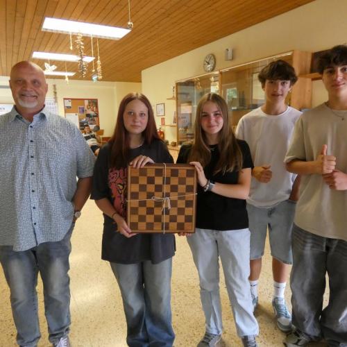 Berufsschullehrer mit 4 Schüler:innen, die ein selbstgemachtes Schachbrett herzeigen
