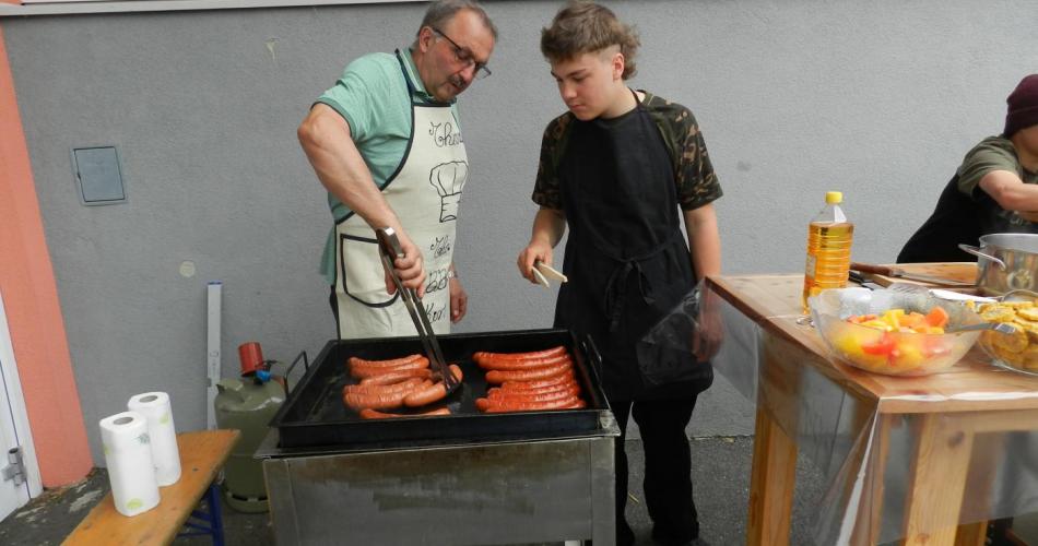 Lehrer und Schüler grillen Bratwurst und Fleisch