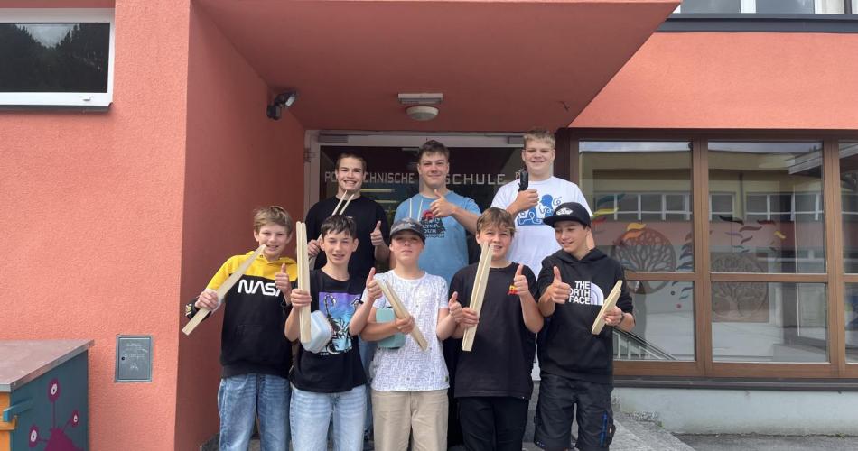 Schüler der PTS und der 3. Klasse Mittelschule mit Holzgrillzangen in der Hand